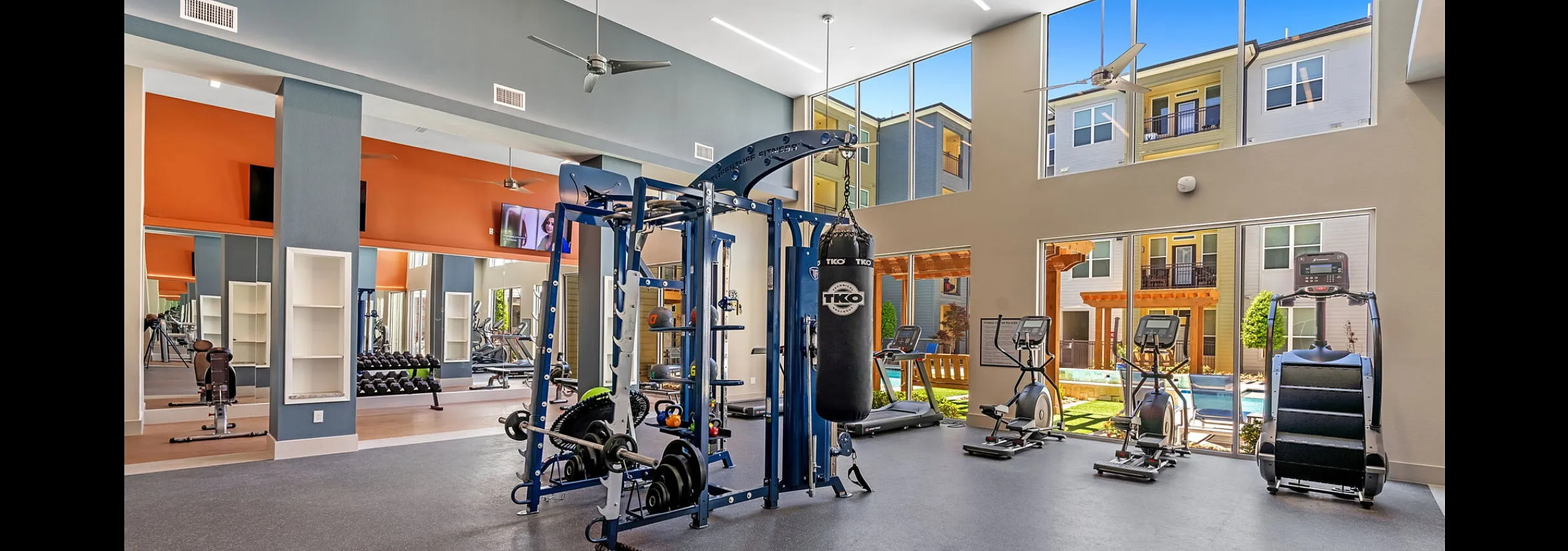Modern fitness center featuring state-of-the-art gym equipment, cardio machines, and spacious design with pool view.