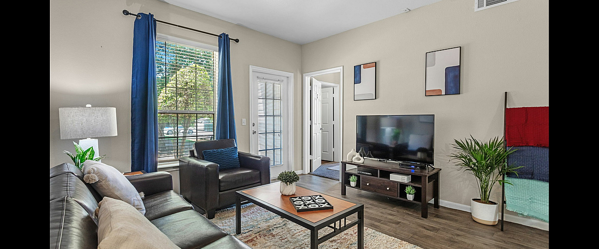 Chic living room with stylish decor, featuring a comfortable leather sofa, plush armchairs, vibrant blue curtains, and a sleek entertainment setup.