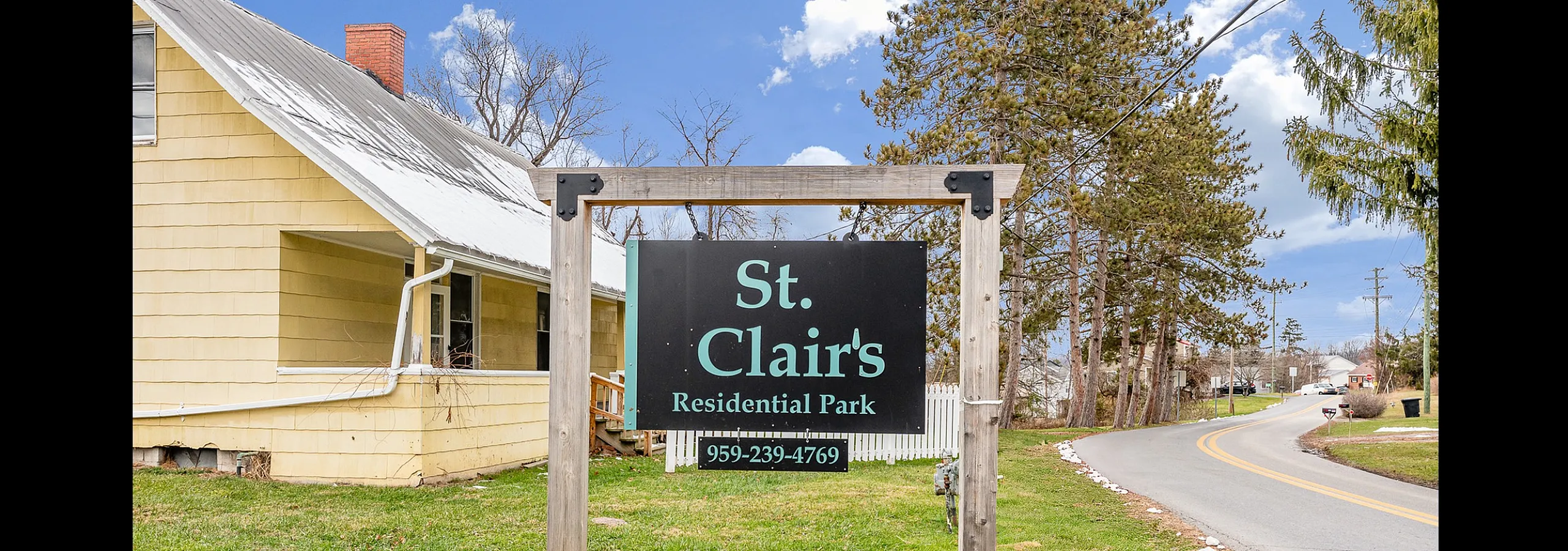Charming entrance to St. Clair's Residential Park, featuring a rustic sign set against a picturesque countryside road.