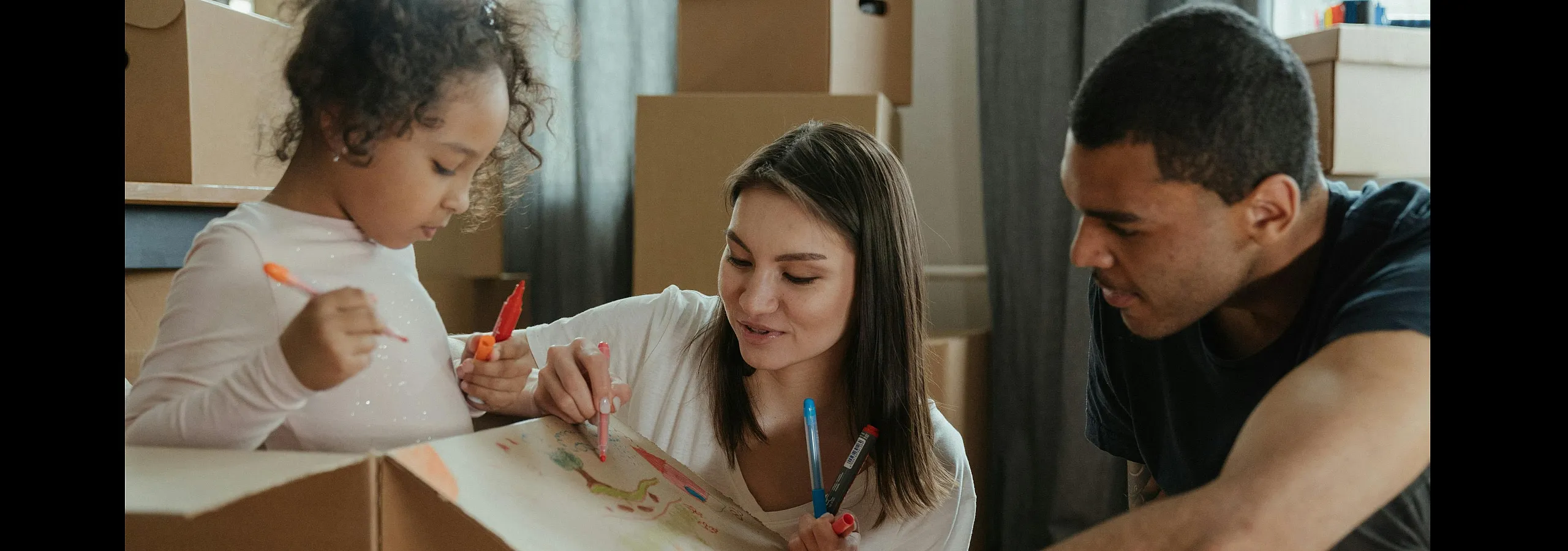 Happy family creating art together during a move, surrounded by packing boxes. Inviting apartment lifestyle perfect for families.