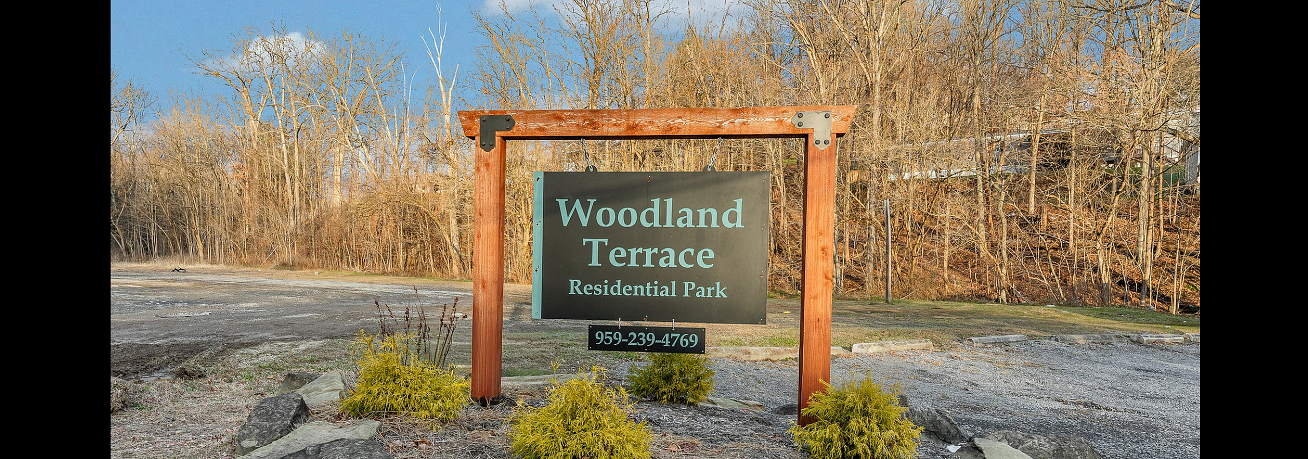 Charming entrance sign of Woodland Terrace Residential Park, surrounded by lush greenery and natural beauty.