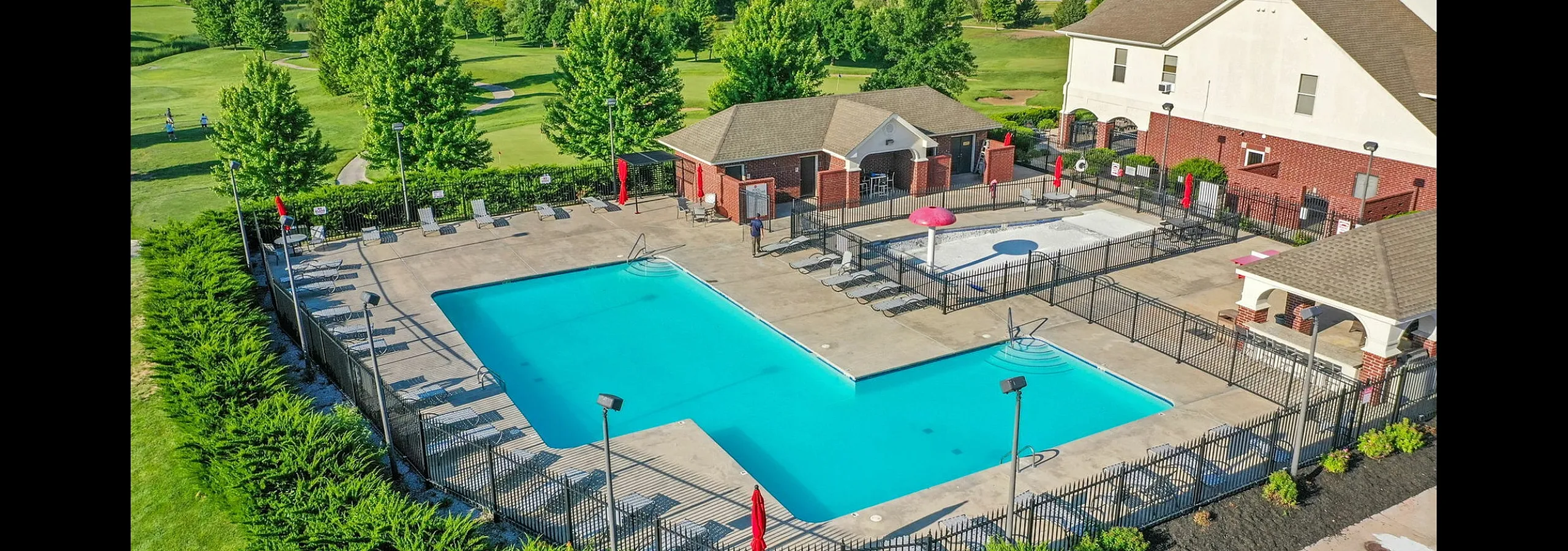 Luxurious apartment community with a large, inviting swimming pool surrounded by manicured greenery and modern amenities, perfect for relaxation and leisure.