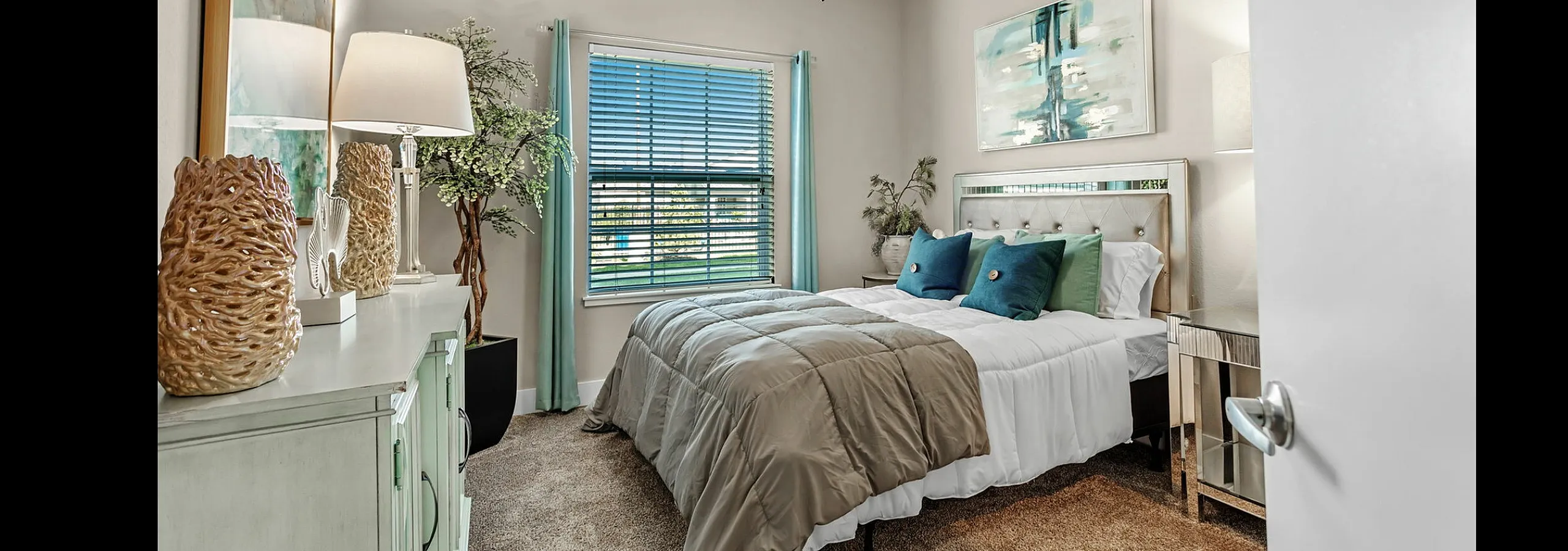 Elegant bedroom with plush bedding, stylish decor, and natural light from large window.