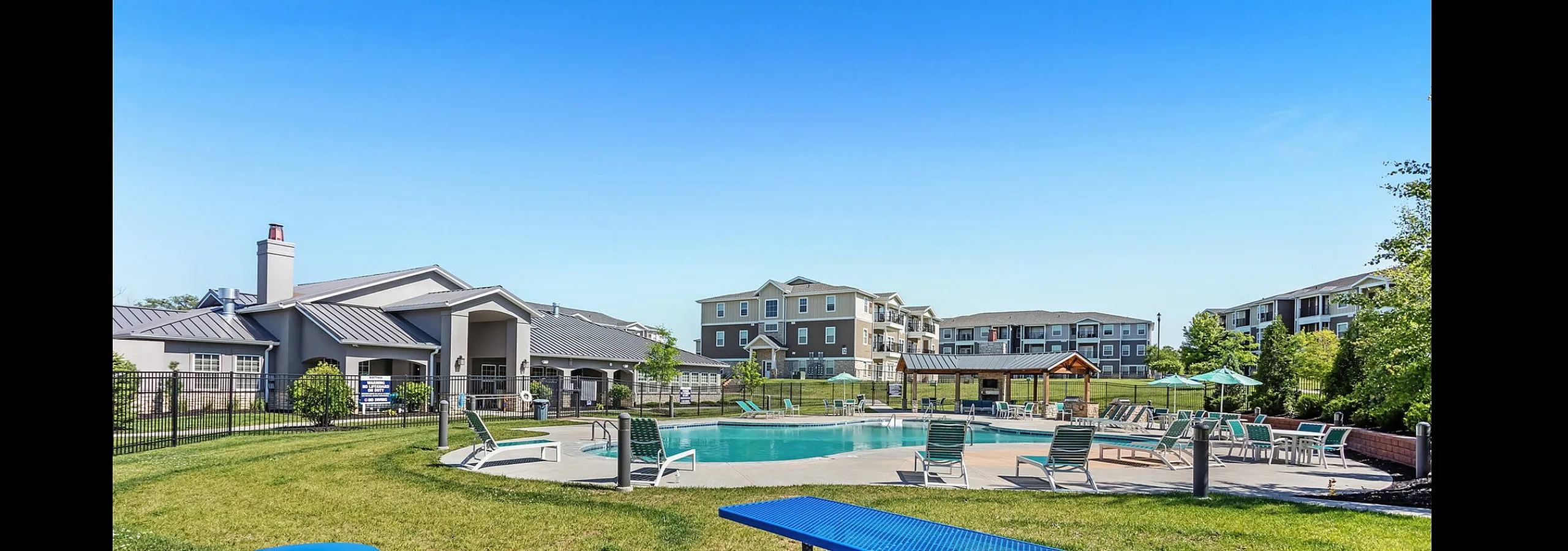 Inviting apartment complex with a serene outdoor pool area, surrounded by modern buildings and green spaces, perfect for relaxation and leisure activities.