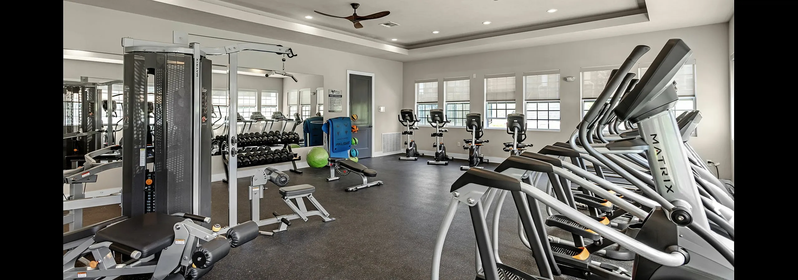Spacious modern gym with top-of-the-line equipment, featuring treadmills, exercise bikes, and diverse weight training machines.