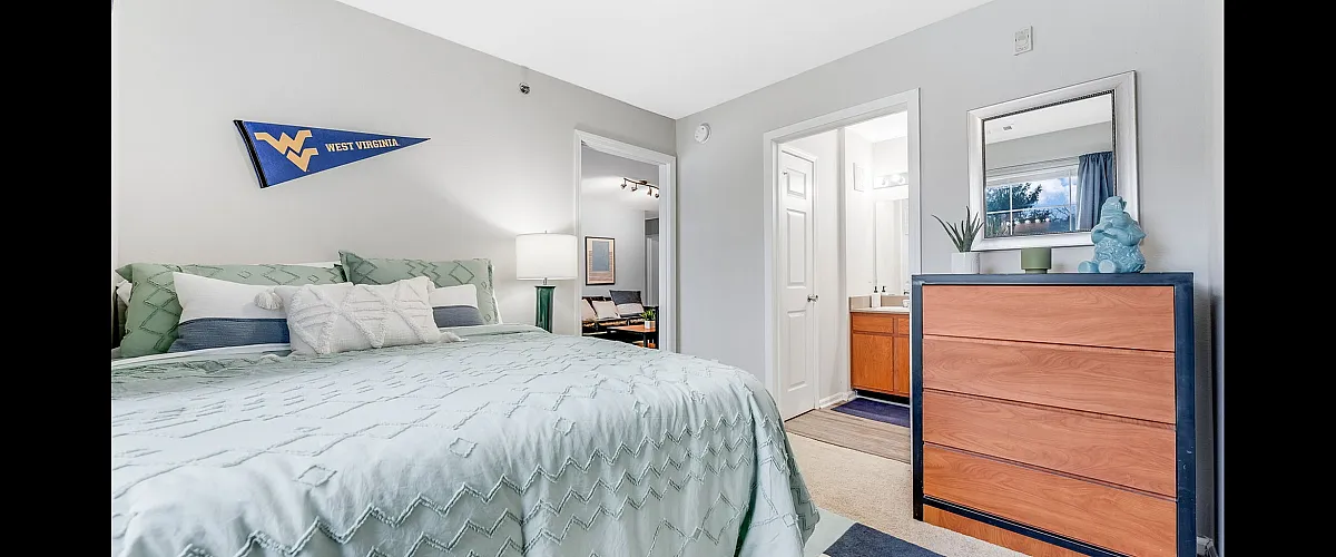 Charming bedroom with cozy bedding, stylish dresser, and en-suite bathroom, ideal for relaxation and convenience.