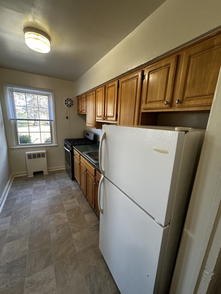 Charming galley kitchen featuring oak cabinetry, sleek appliances, and cozy natural light.