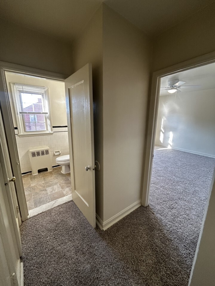 Cozy hallway leading to a bright bedroom and a charming bathroom with classic tiles.