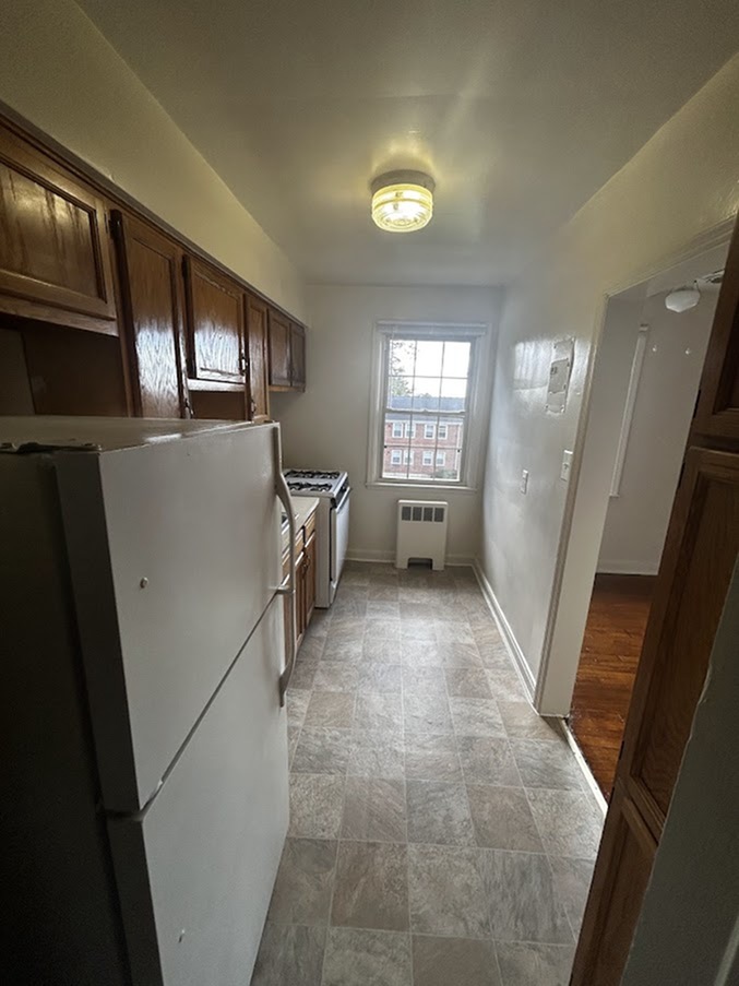 Cozy galley kitchen with ample wooden cabinetry, a large window allowing natural light, and modern appliances.