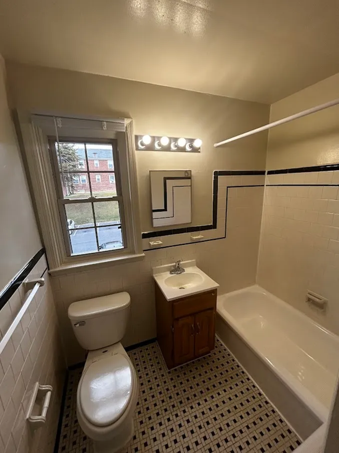Cozy bathroom with elegant black and white tiles, a sleek vanity, and a bright window view.