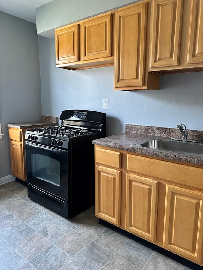 Charming kitchen featuring sleek black stove, wooden cabinetry, and elegant countertops.