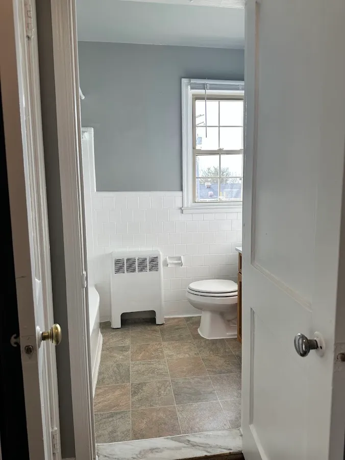 Bright bathroom with sleek tiles, a large window, and modern amenities showcasing elegance and functionality.