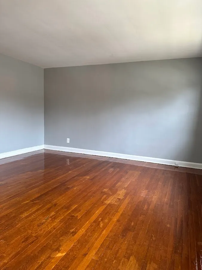 Bright and spacious room featuring elegant hardwood flooring and neutral gray walls, perfect for personalized decor.