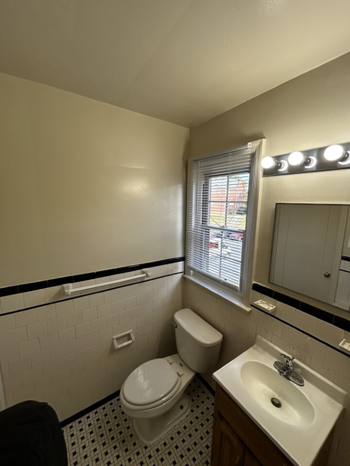 Charming bathroom with classic tile flooring, elegant white fixtures, and a bright window bringing in natural light.