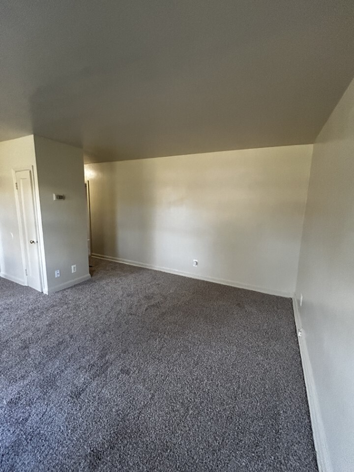 Spacious living area with fresh neutral walls and plush carpet flooring, ready for personal touch and cozy furnishings.