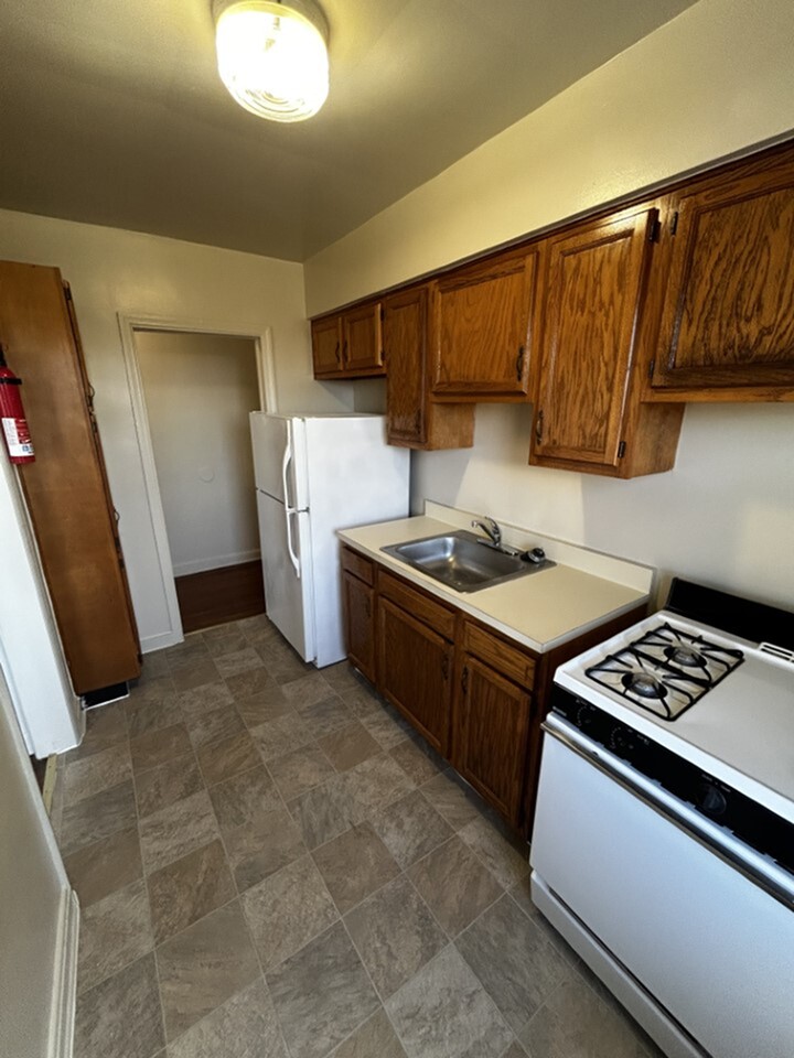 Cozy kitchen with wooden cabinets, a gas stove, and a bright overhead light for a welcoming atmosphere.