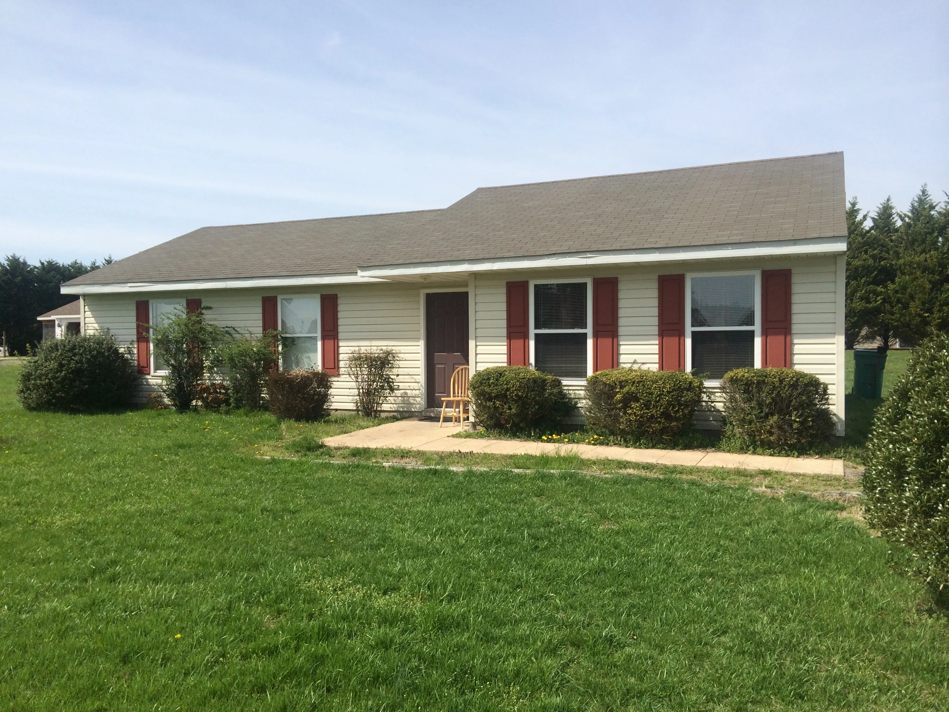 Charming single-story home with a cozy exterior, featuring red shutters and a neatly landscaped front yard.
