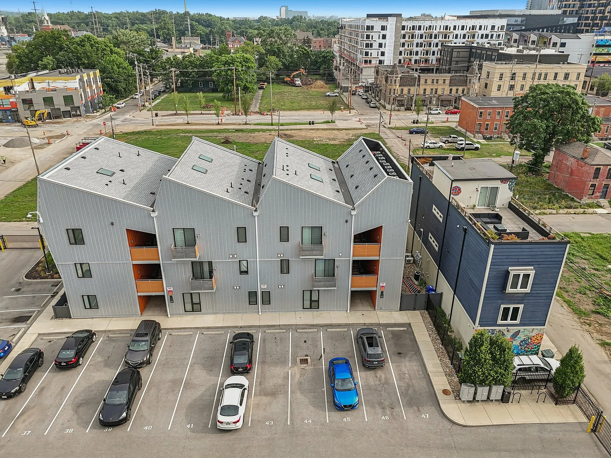 Modern apartment complex with unique angled roofs and vibrant urban surroundings, featuring convenient parking and easy access to nearby amenities.
