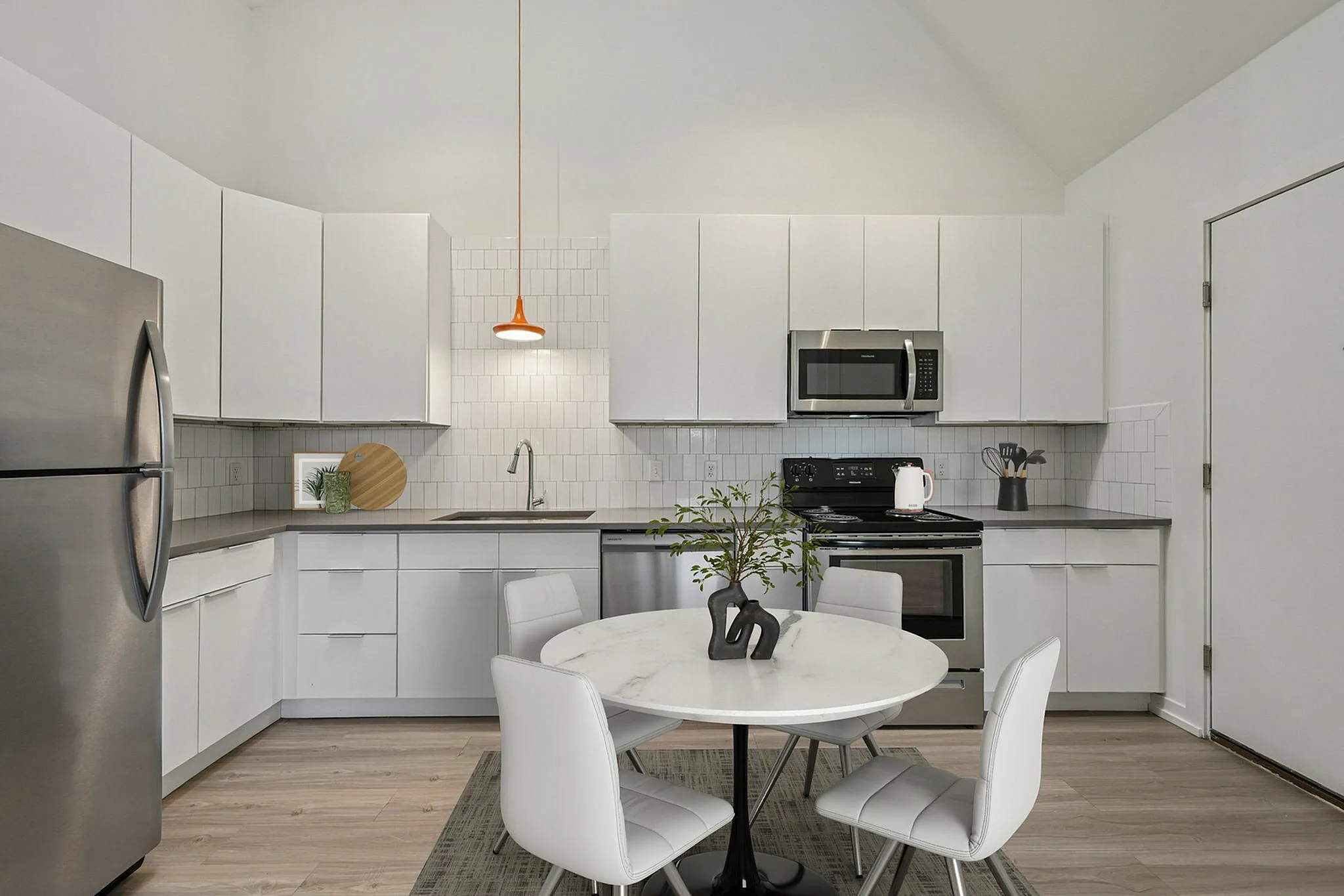 Modern kitchen with sleek white cabinetry, stainless steel appliances, and a cozy dining area.