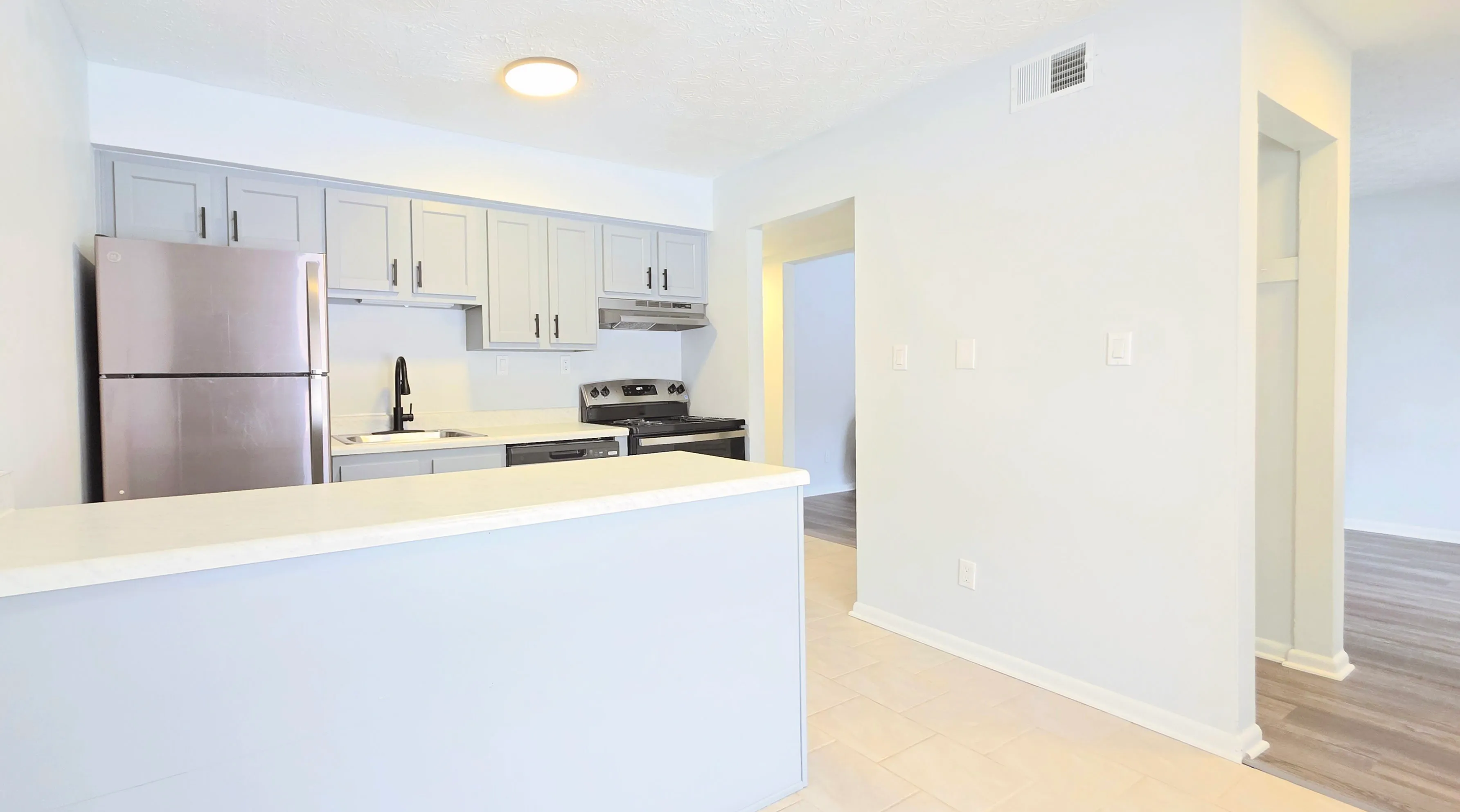 Modern kitchen with sleek gray cabinetry, stainless steel appliances, and elegant white countertops, perfect for culinary enthusiasts.