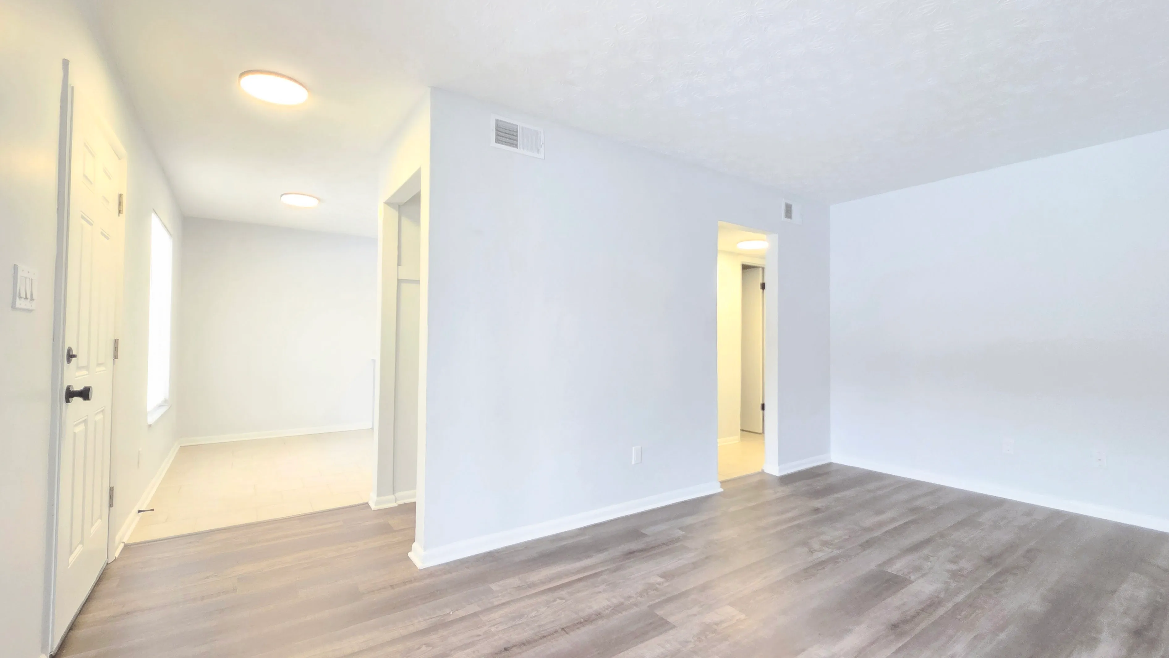 Bright and inviting open space with elegant wood flooring and ample natural light, perfect for modern living.
