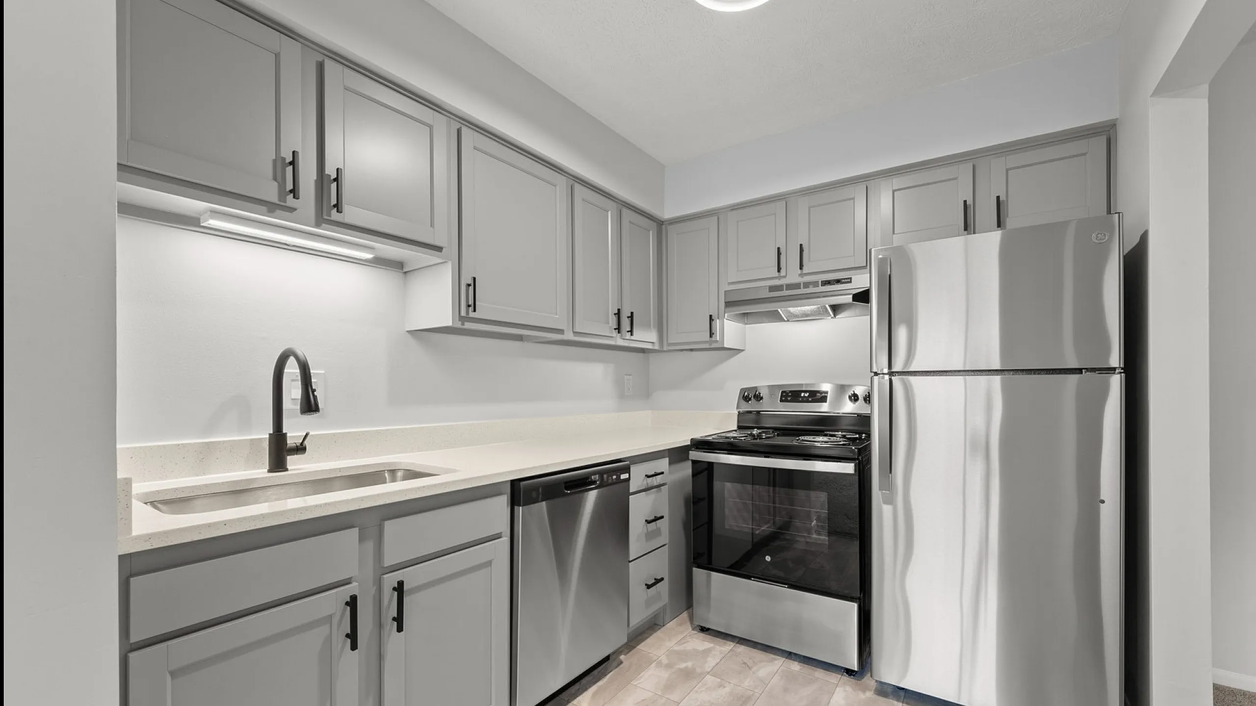Modern kitchen with sleek gray cabinetry, stainless steel appliances, and elegant stone countertops.