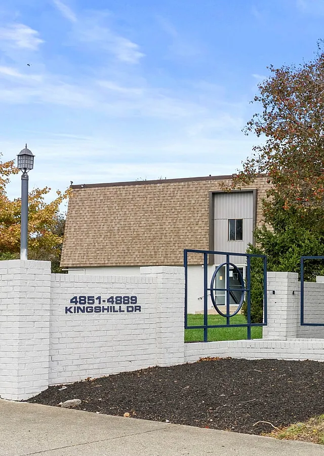 Inviting entrance of Center Court Apartments with modern signage, lush greenery, and seasonal decorations at 4851-4889 Kingshill Drive.