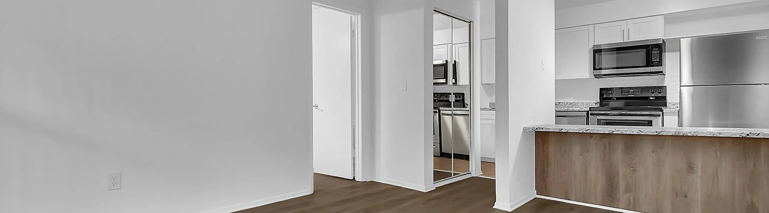 Bright open-concept living space with elegant wood flooring, sleek modern kitchen featuring stainless steel appliances and granite countertops, ideal for stylish urban living.