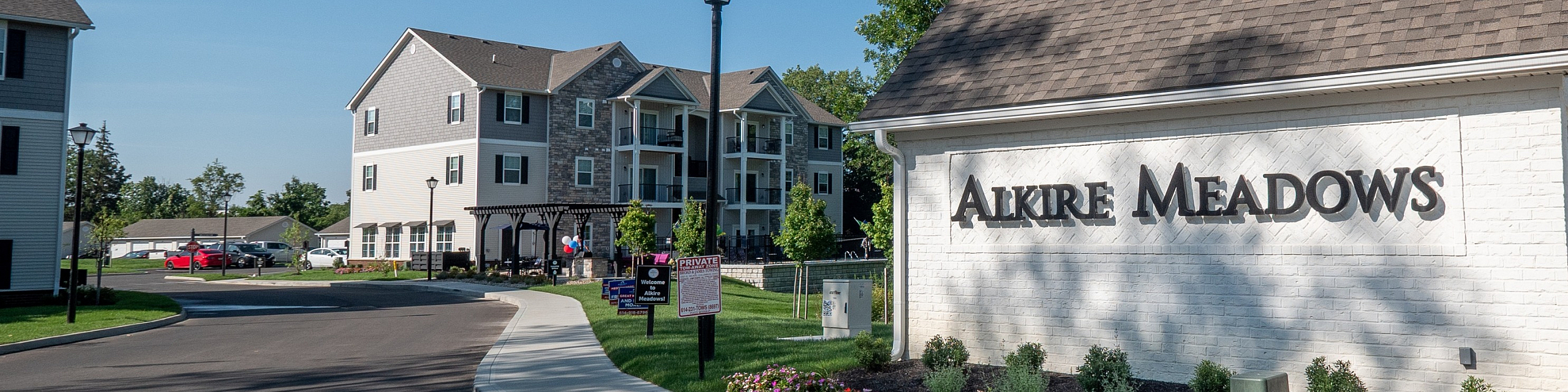 Welcome to Alkire Meadows, featuring charming apartment buildings surrounded by lush greenery and vibrant gardens.