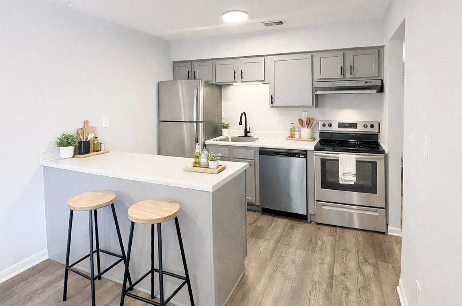 Modern kitchen with sleek gray cabinetry, stainless steel appliances, and a cozy breakfast bar with stylish stools.