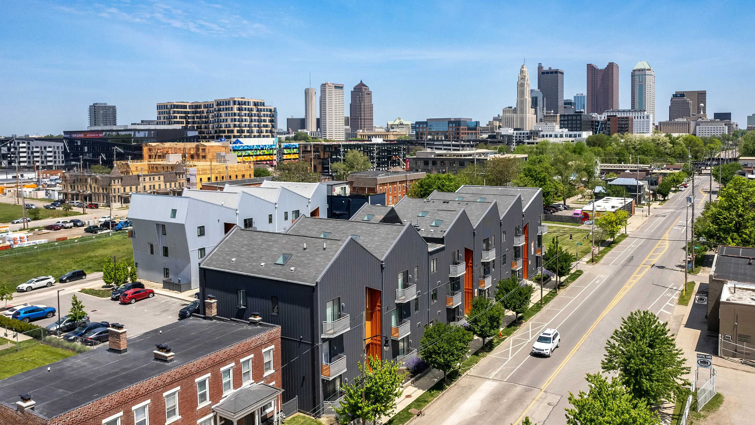 Vibrant urban neighborhood showcasing modern townhouses against a stunning city skyline, perfect for contemporary living.