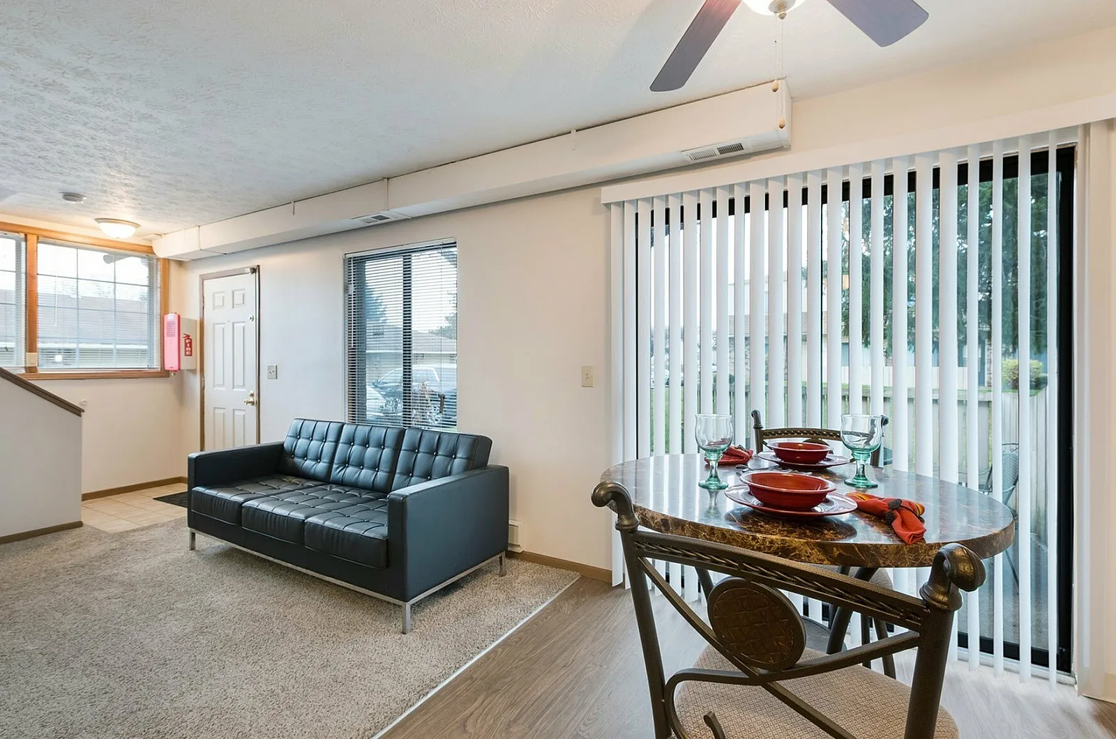 Inviting open living space with elegant dining area, featuring a sleek leather sofa and bright, airy windows.