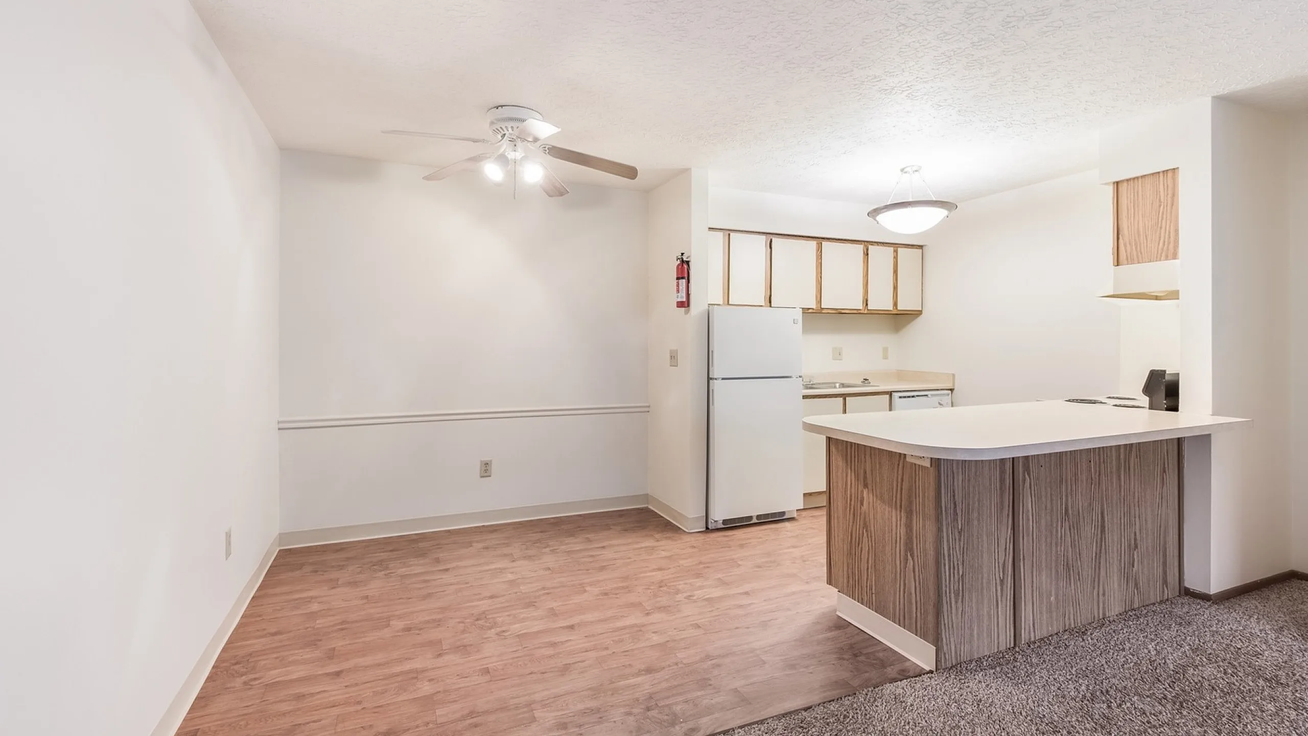 Inviting open-concept apartment kitchen and dining area with warm wood floors, modern light fixtures, and charming countertop.