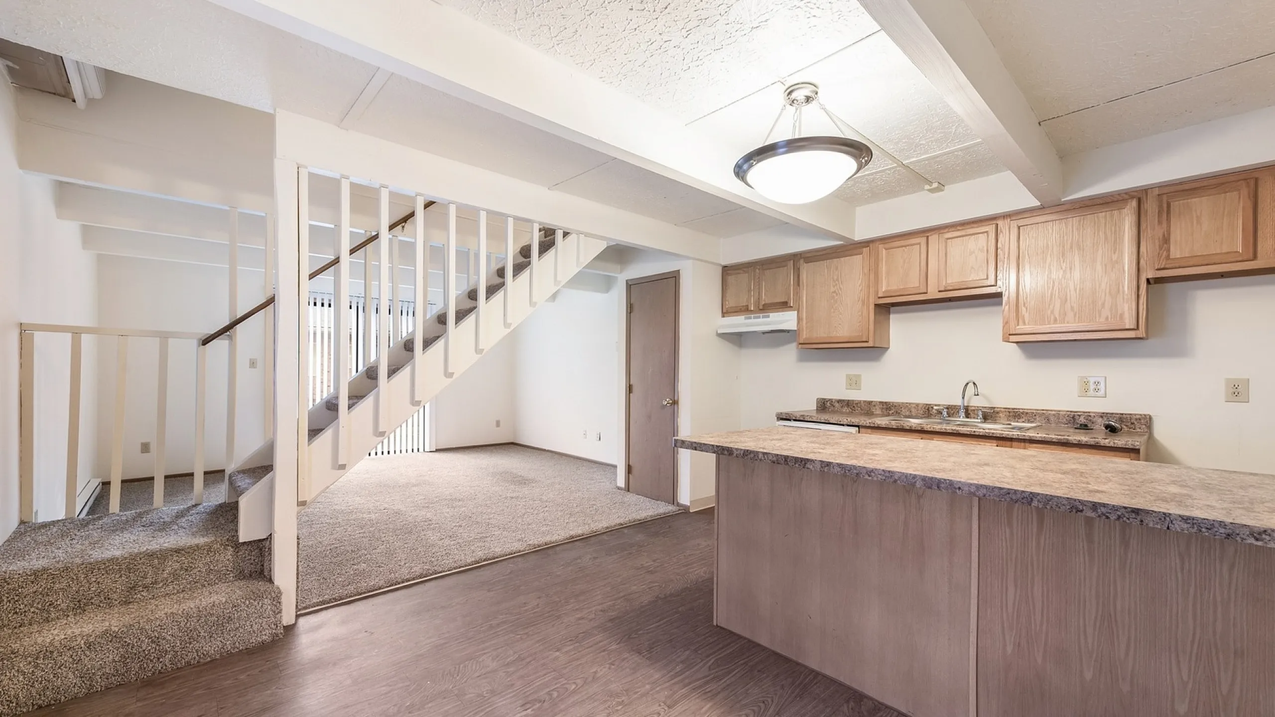 Welcoming open-plan layout with modern kitchen, airy living area, and inviting staircase, perfect for family living.