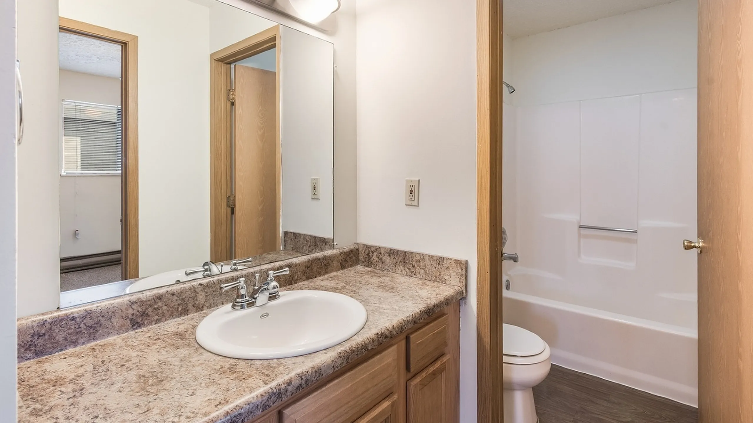 Bright and inviting bathroom with elegant marble countertop, spacious mirror, and modern lighting fixtures.