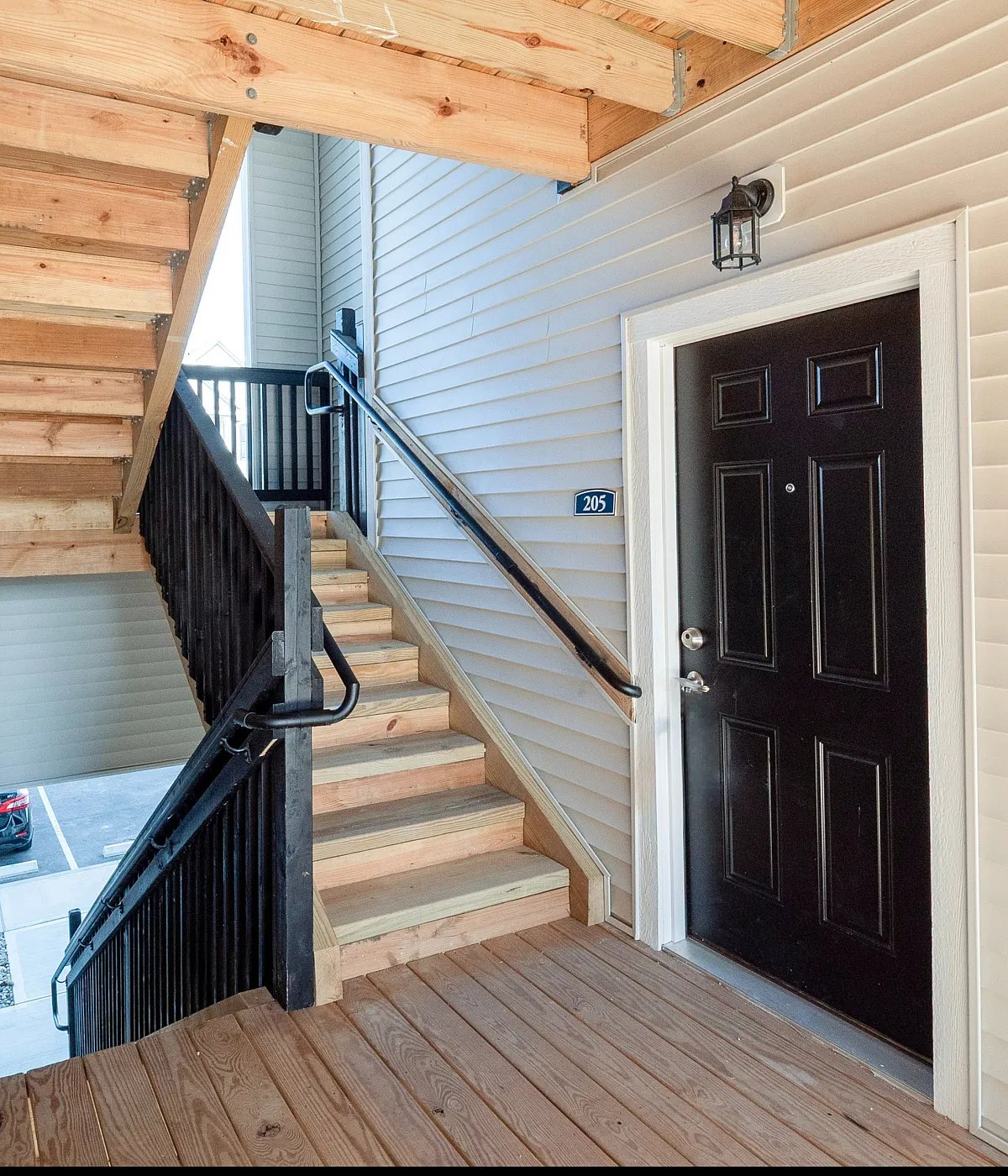 Inviting apartment entrance with warm wood detailing and elegant outdoor staircase, offering a charming and modern welcome.
