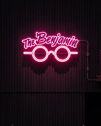 Chic urban apartment facade featuring a vibrant neon sign with stylish glasses design.