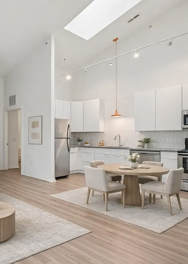 Bright and modern living space featuring an open-plan kitchen, elegant dining area, and cozy sofa in a stylishly decorated apartment.