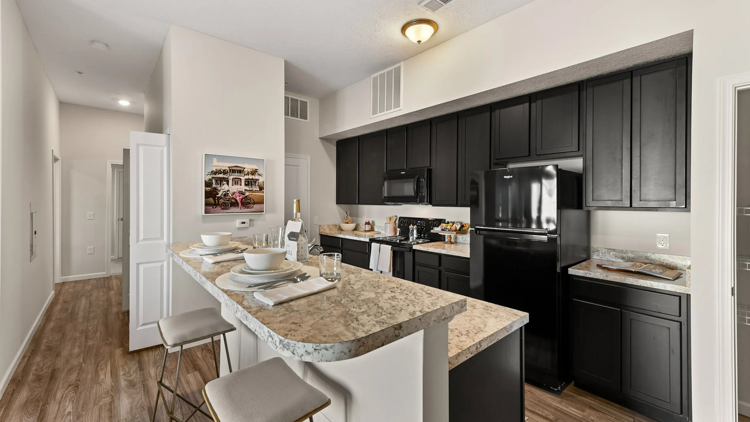 Modern kitchen with sleek black cabinetry, granite countertops, and a charming breakfast bar setup with elegant dining pieces.