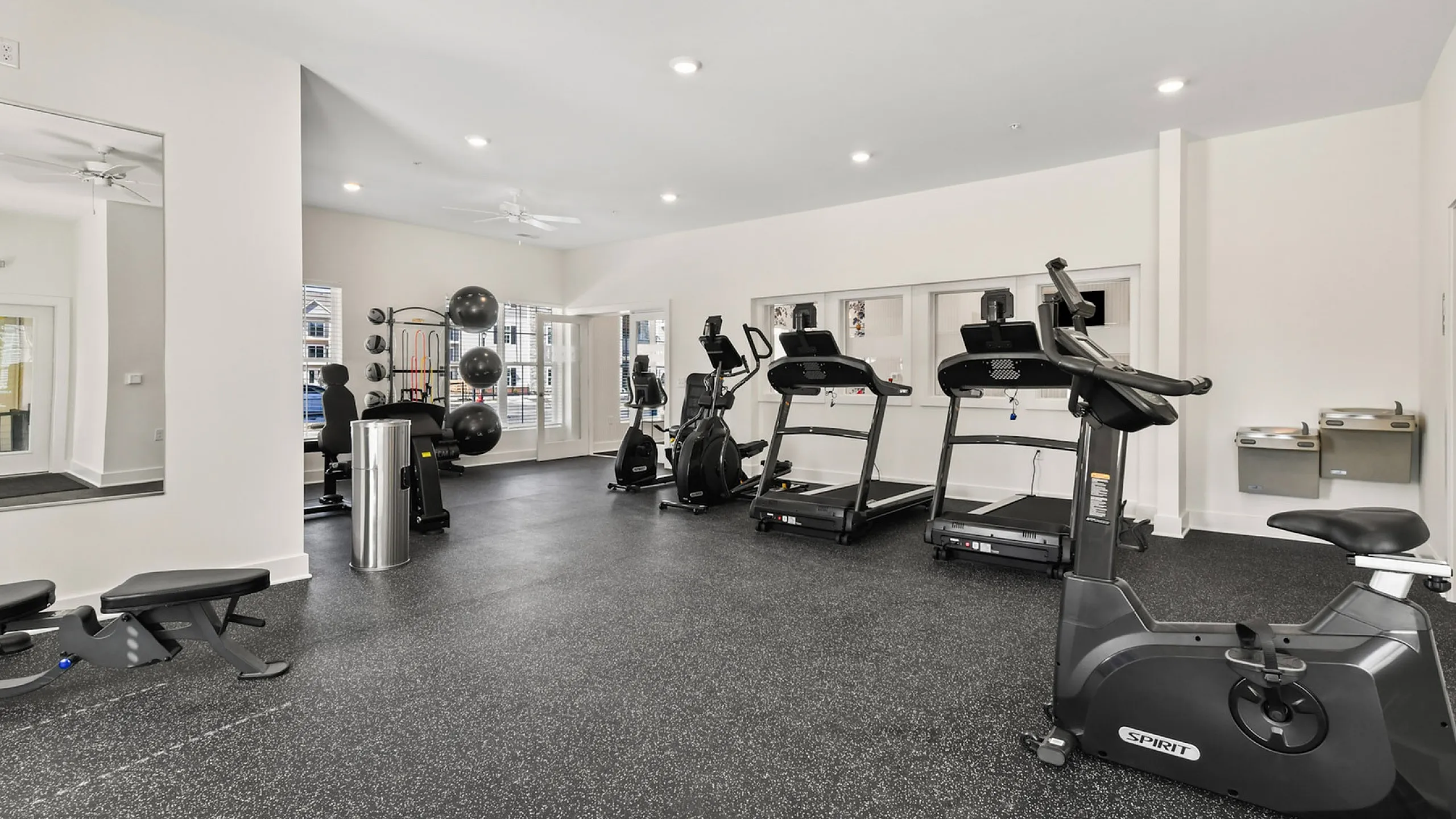 Modern fitness center with treadmills, exercise bike, and yoga equipment in a bright, spacious room.