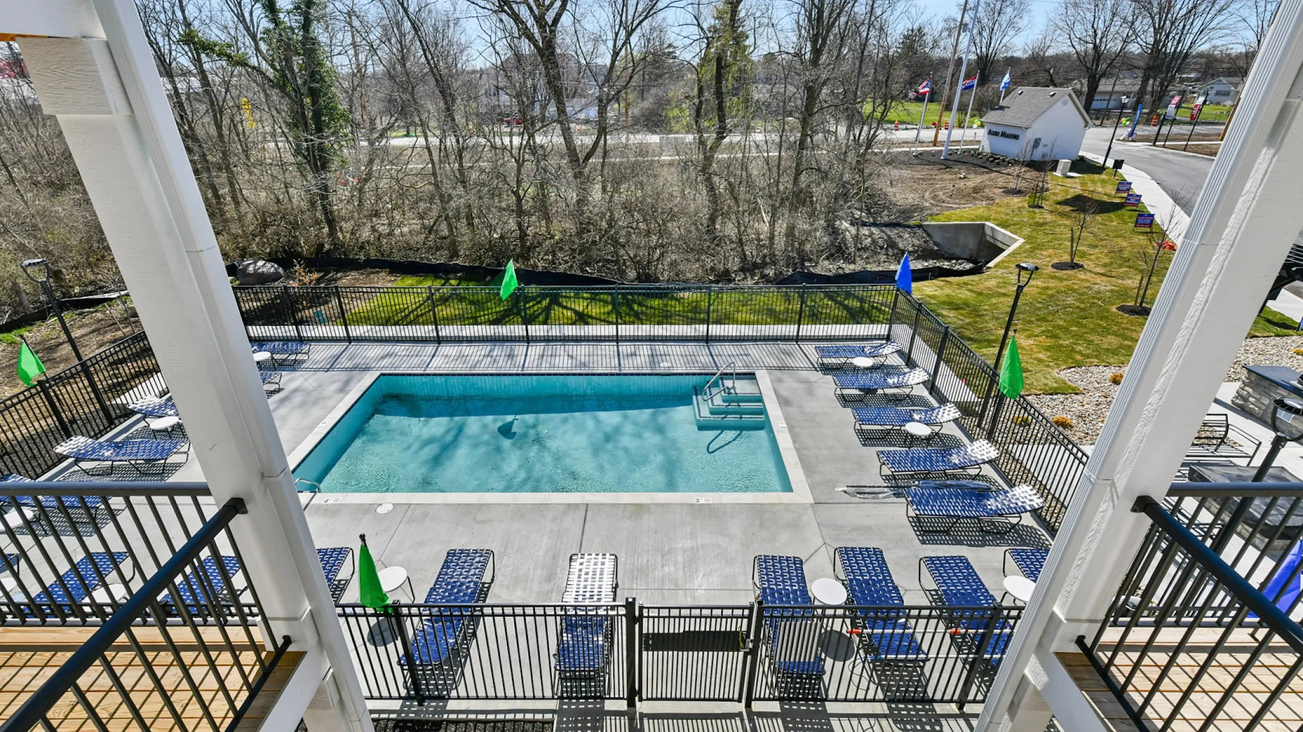Inviting outdoor pool area with stylish lounge chairs and vibrant flags, surrounded by lush greenery for a relaxing retreat.