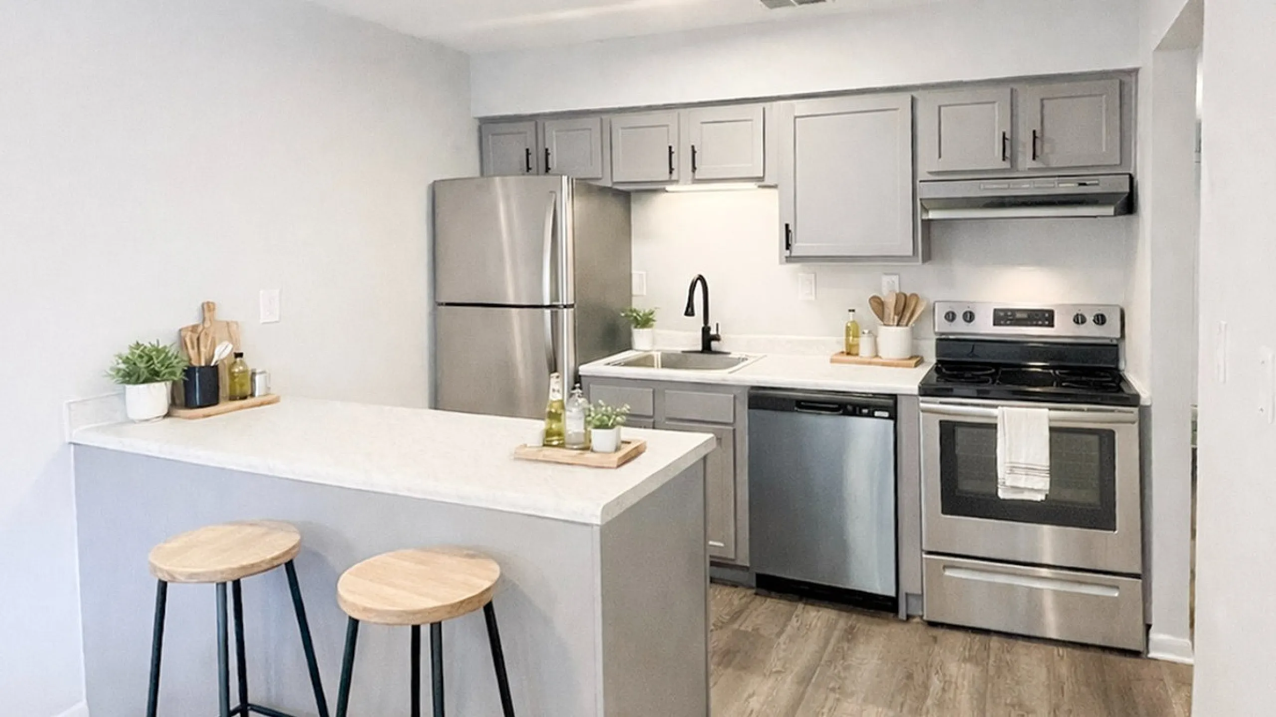Chic modern kitchen with sleek gray cabinets, stainless steel appliances, and a cozy breakfast bar with stylish stools.