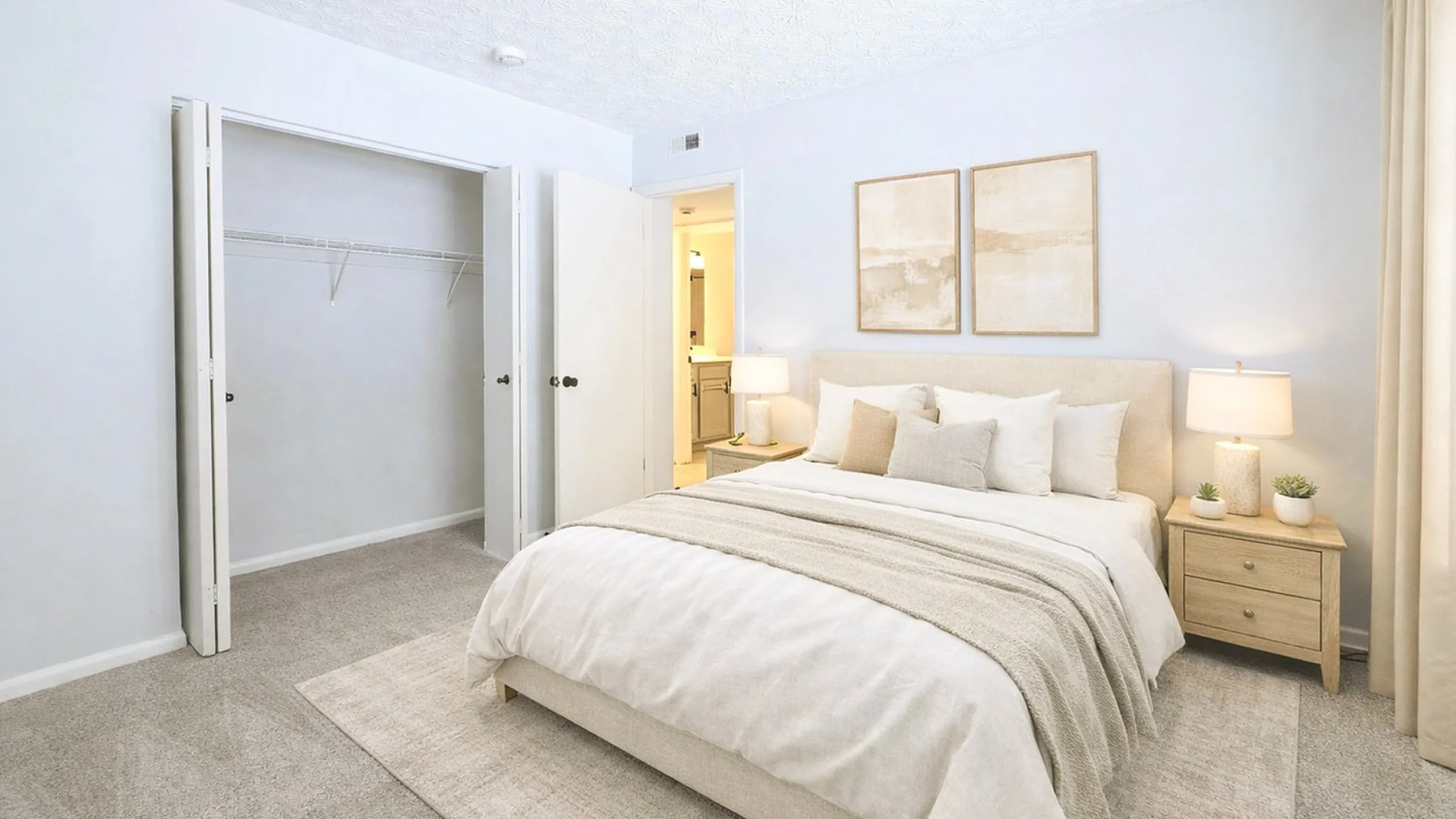 Bright and airy bedroom featuring a plush bed with neutral tones, soft carpet, open closet, and modern decor for a serene atmosphere.