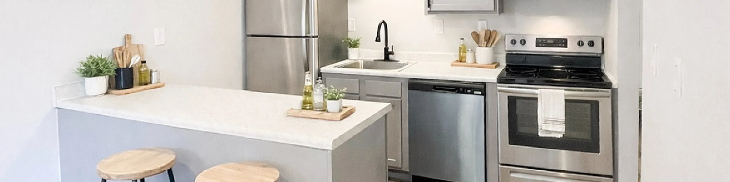 Modern kitchen with sleek stainless steel appliances, elegant gray cabinetry, and stylish wooden bar stools.