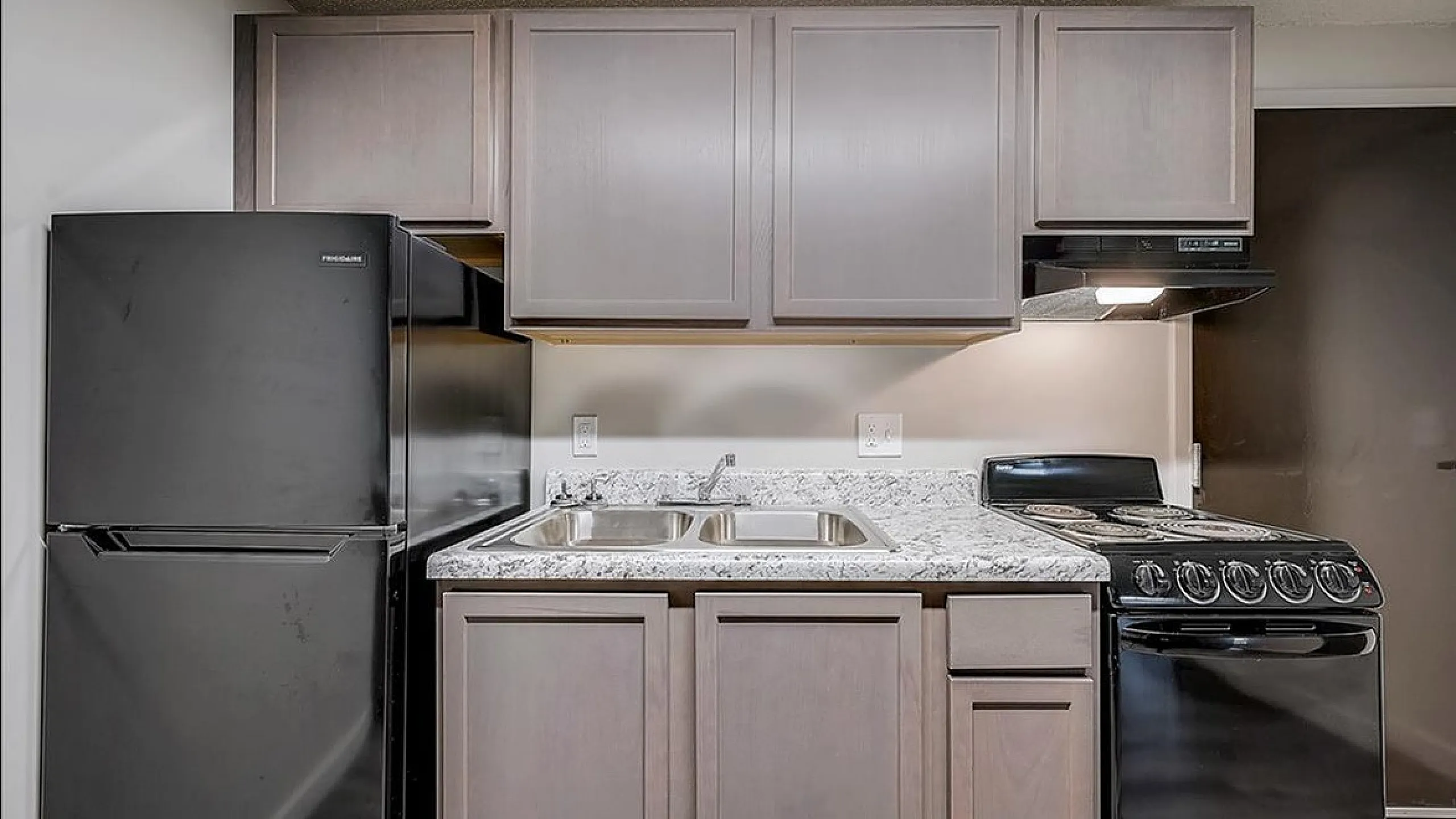 Modern kitchen with elegant cabinetry, sleek black appliances, and a stylish granite countertop.