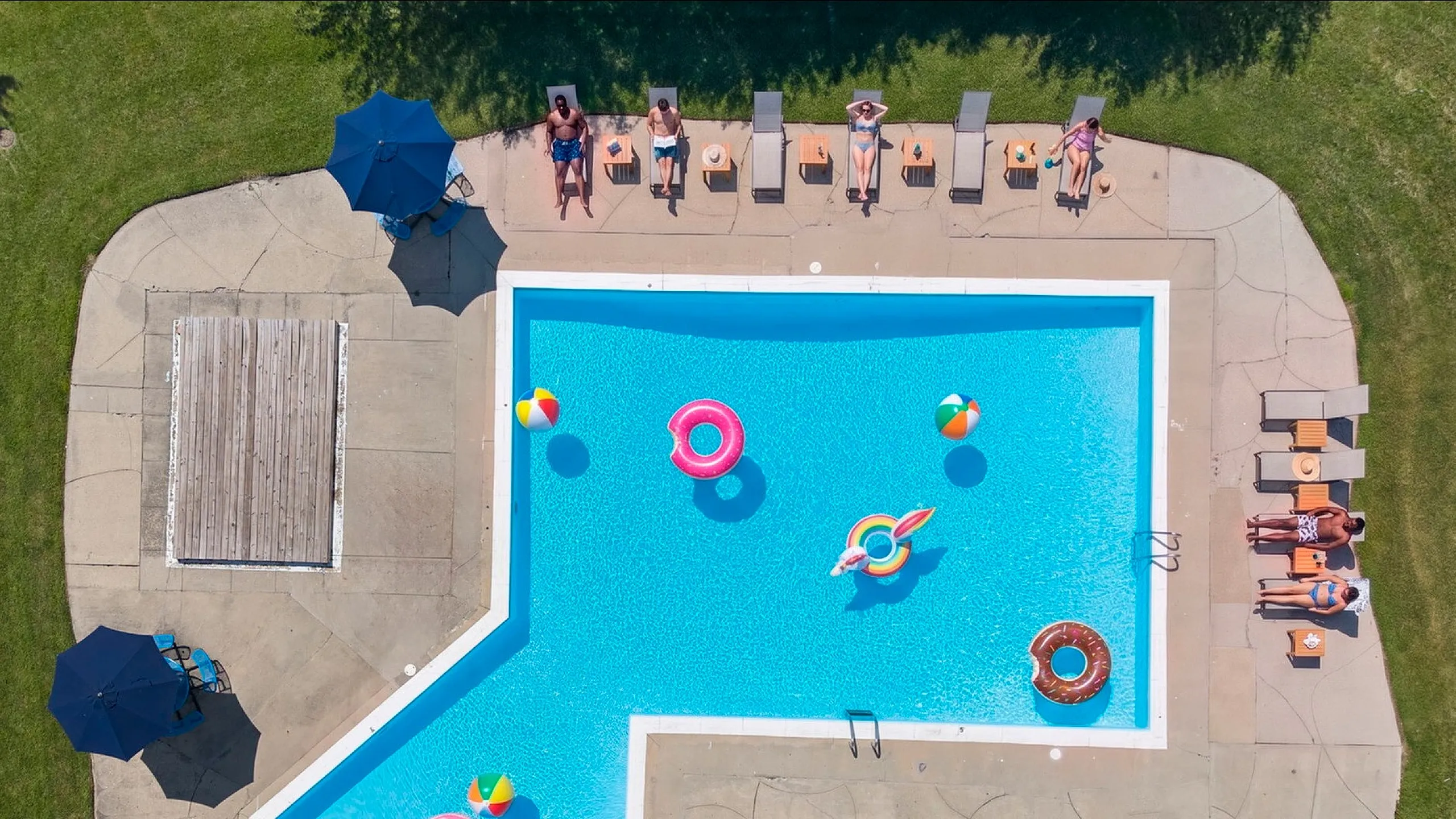 Inviting outdoor pool with vibrant floaties and sun loungers, perfect for relaxation and fun.