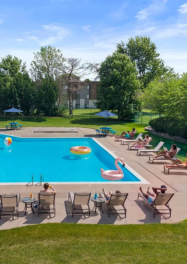 Inviting outdoor pool with lounge chairs and vibrant floats, perfect for relaxation and summer fun, surrounded by lush greenery.