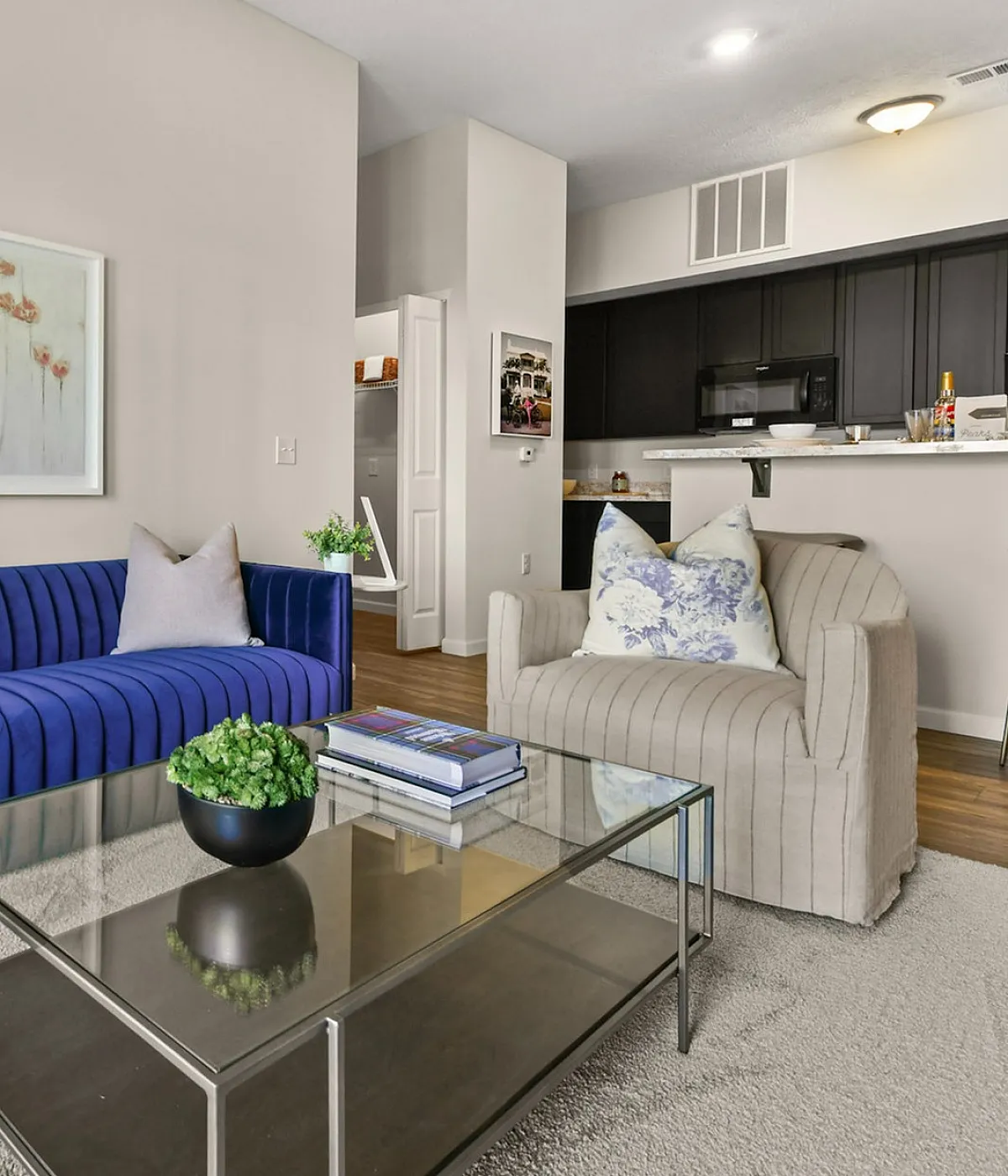 Chic modern living room with vibrant blue sofa, elegant decor, and open kitchen concept.