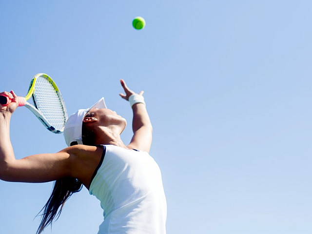 Woman serving tennis ball