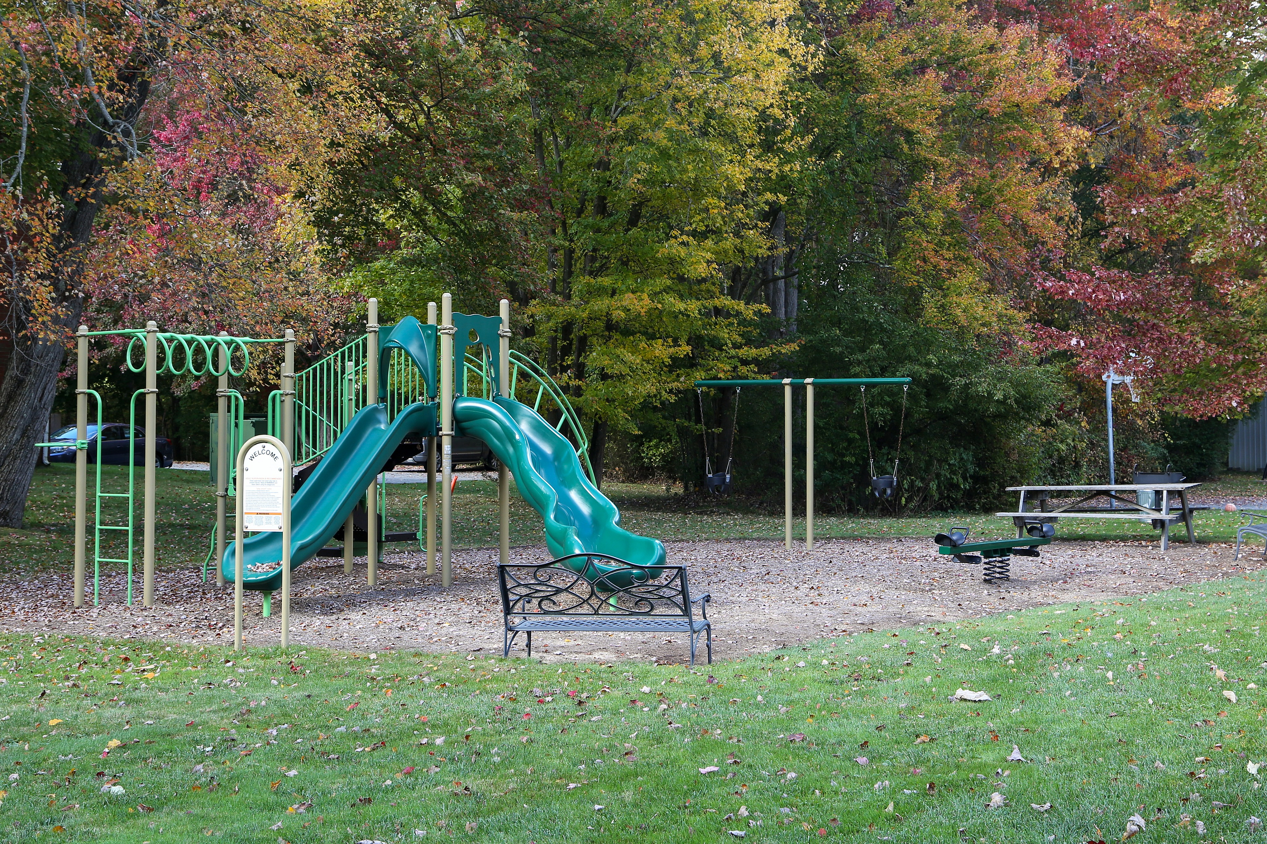 Playground with swings, slide, bench, and picnic table.